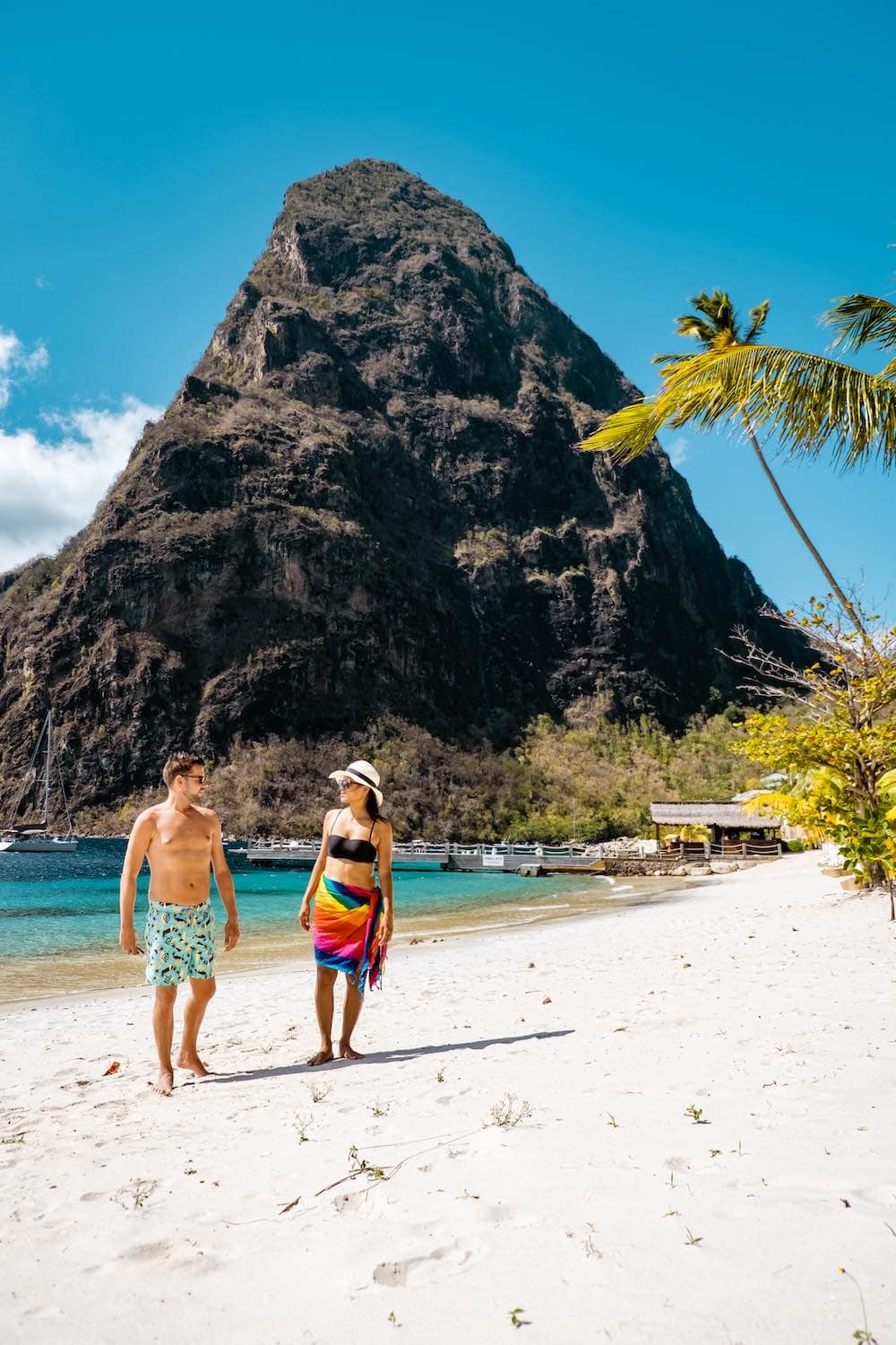 Couple walking on a beach in St. Lucia holding hands on a Caribbean honeymoon.