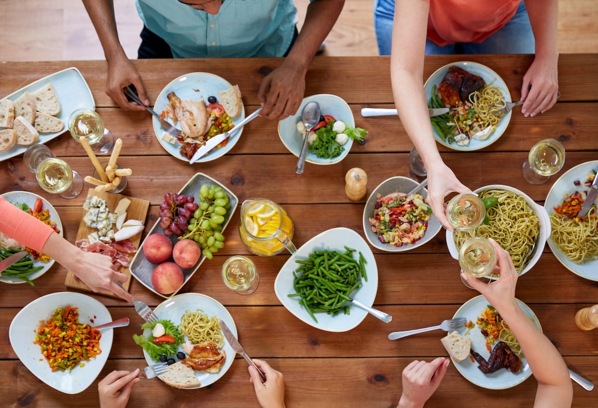 Group of people eating food at a wooden table.