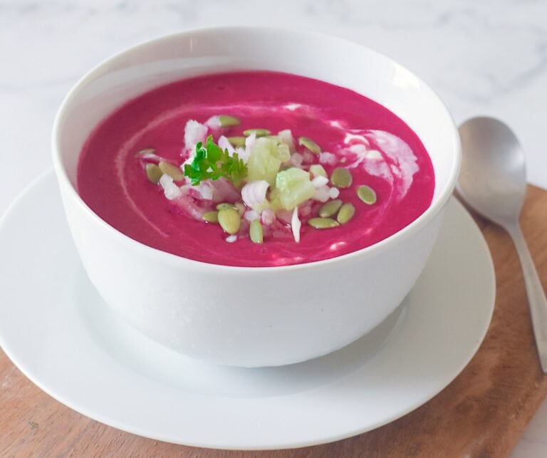 Healthy beet gazpacho with yogurt in a white bowl.