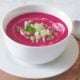 Healthy beet gazpacho with yogurt in a white bowl.