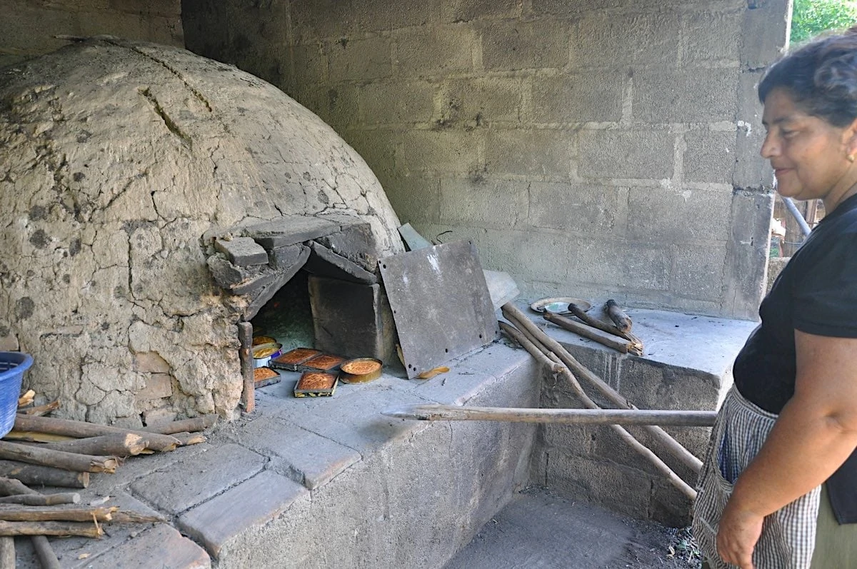 Woman baking quesadilla cakes in an outdoor oven in Zacapa, Guatemala.