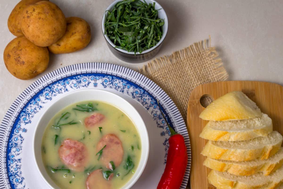 Caldo verde soup is a famous Portuguese dish and is shown served in a white bowl with slices of bread.