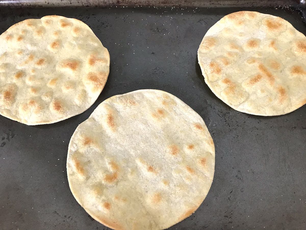 Homemade baked tostadas on a baking sheet.