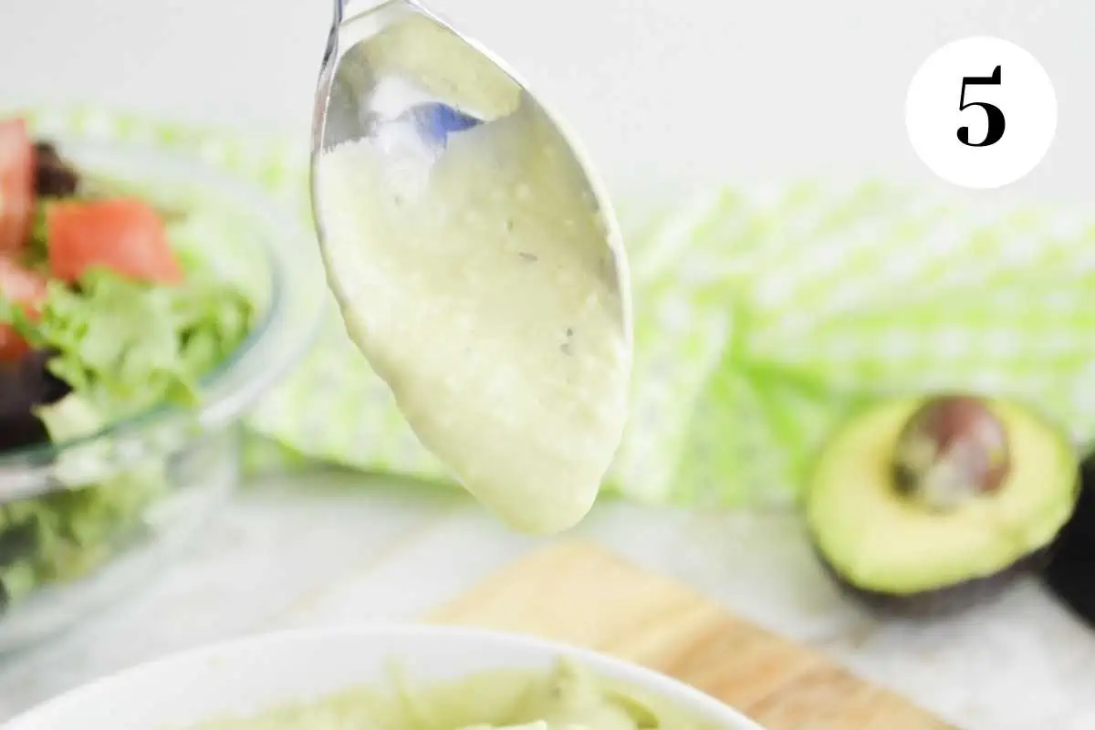 Avocado ranch dressing dripping off a spoon.