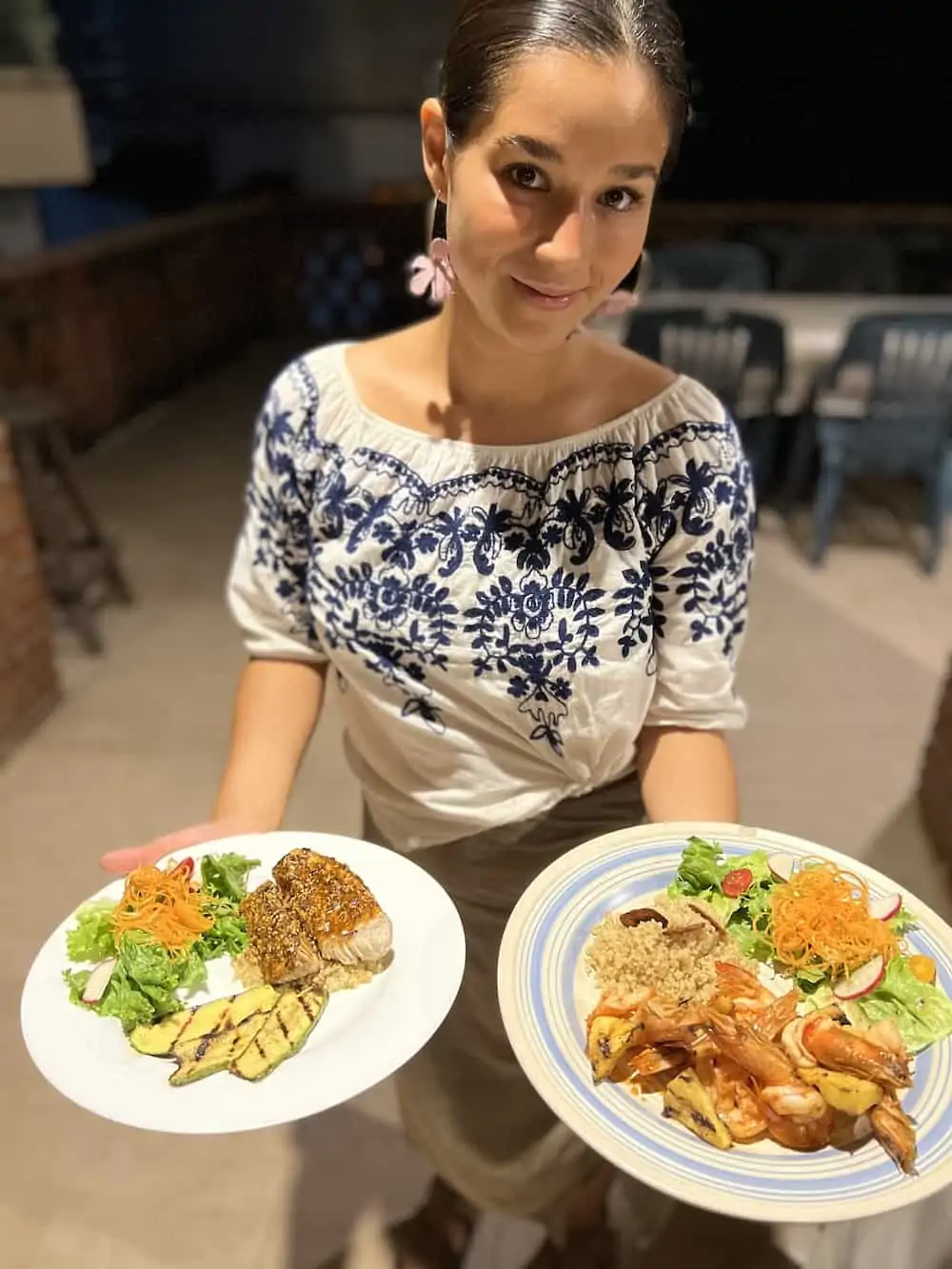 Woman holding two plates of seafood at Escondido restaurant in Mexico.