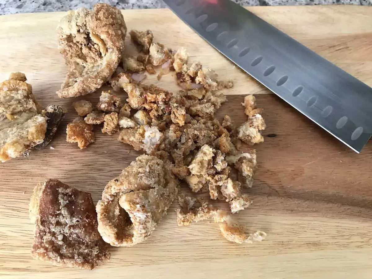 Chopping chicharrones with a knife on a wooden board. 