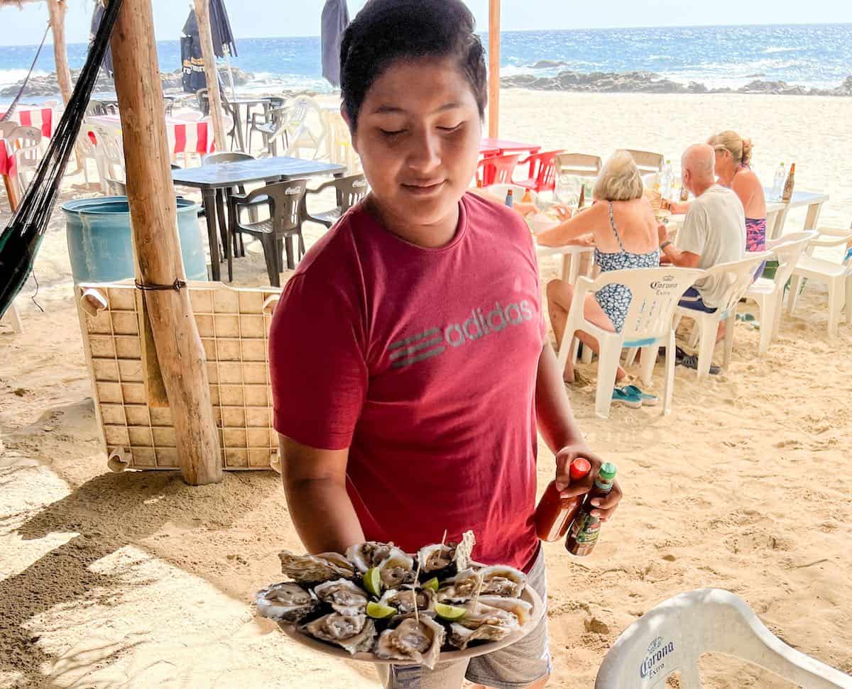 Young man serving oysters at Agua Blanca beach in Oaxaca.