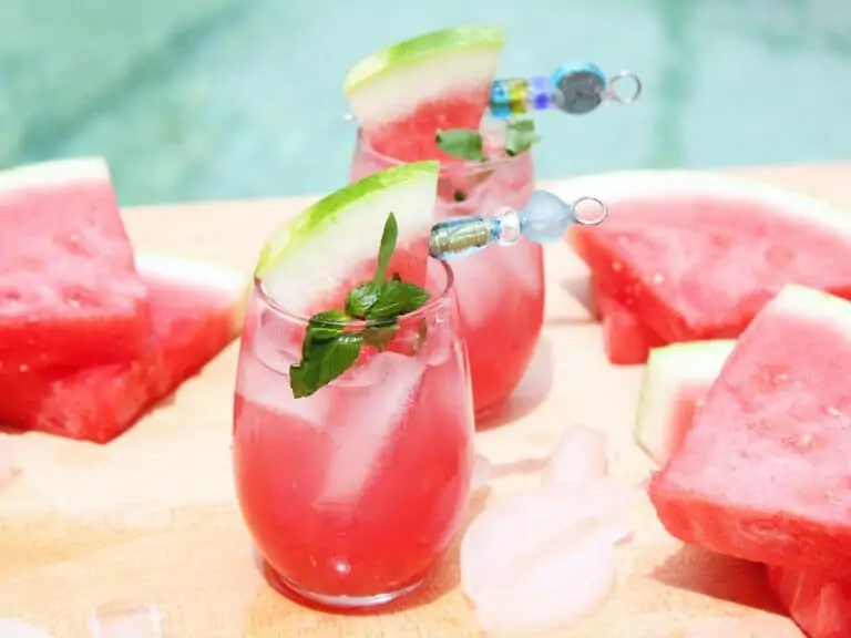 Two glasses of watermelon cocktail by a swimming pool.