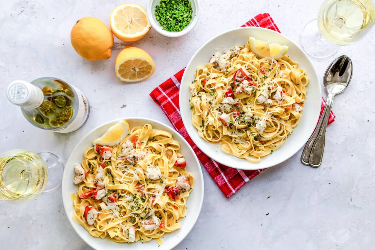 Two bowls of lobster fettuccine with wine.