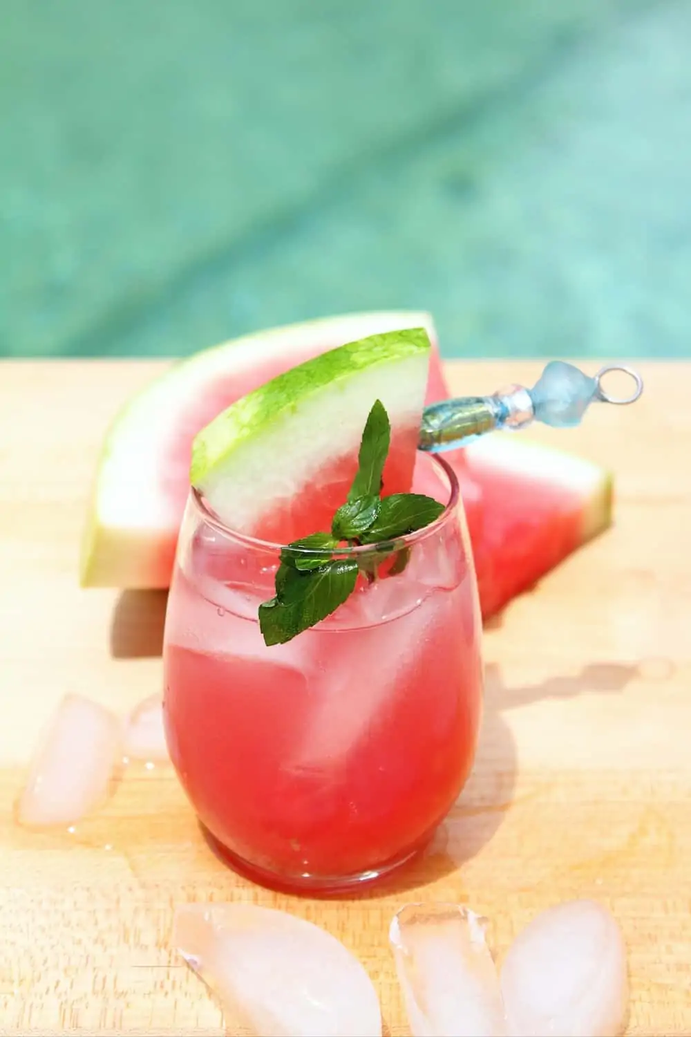 A watermelon drink with vodka in front of a swimming pool. 