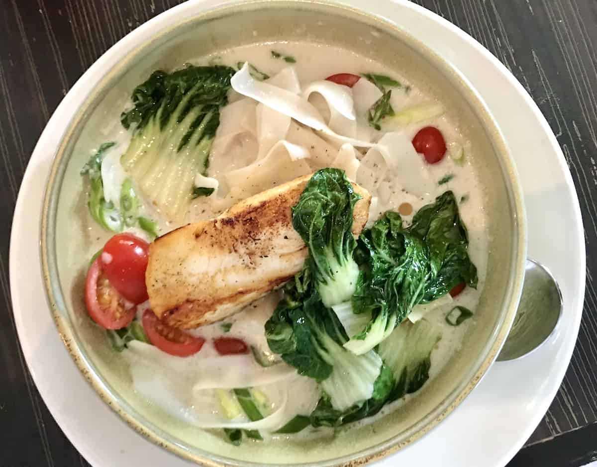 Halibut in Asian-style vegetables in a white bowl at Le Bistro Spa Nordik. 