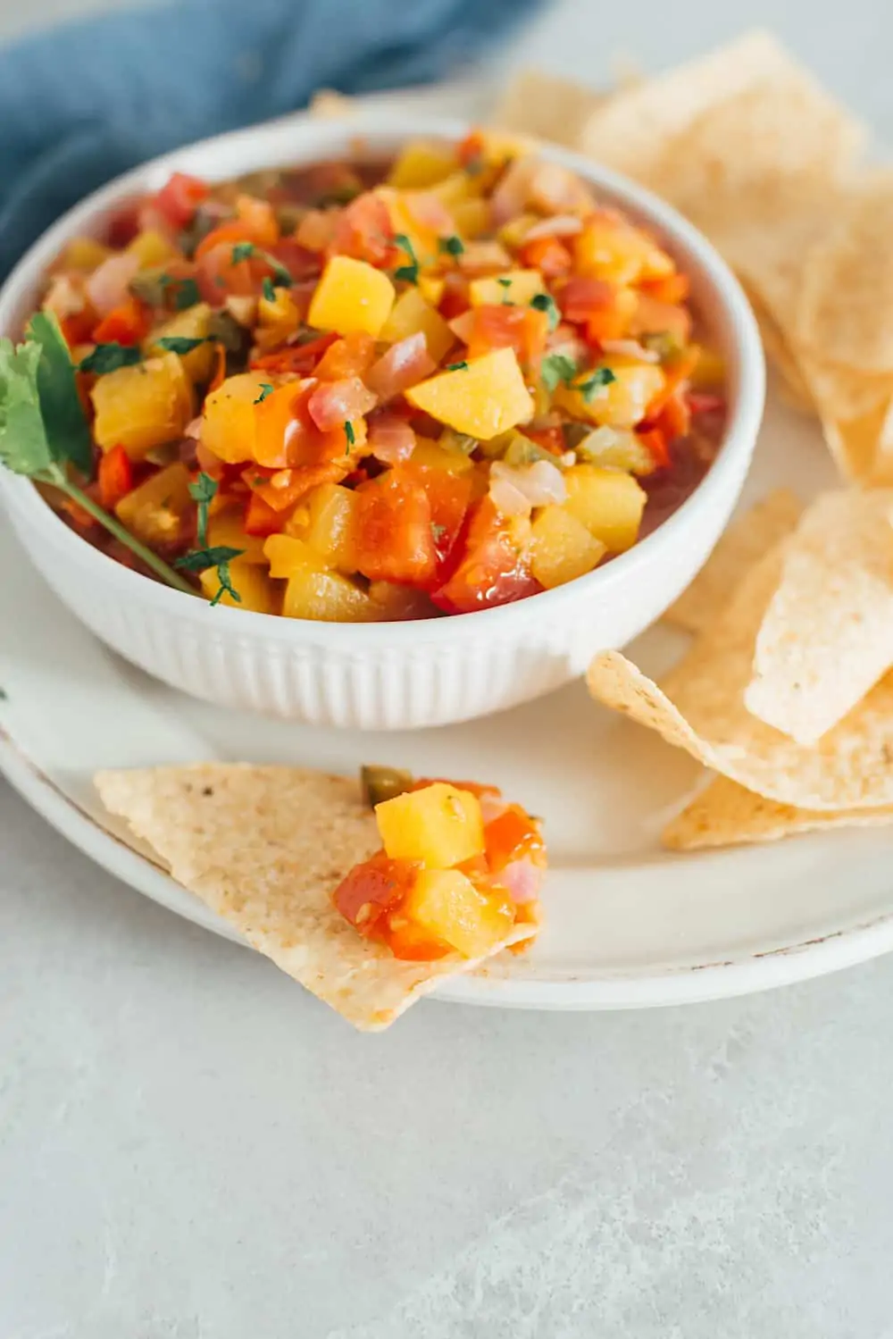 fresh peach chutney with tortilla chips in a white bowl.