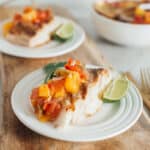 Grilled halibut with peach salsa on white plates.