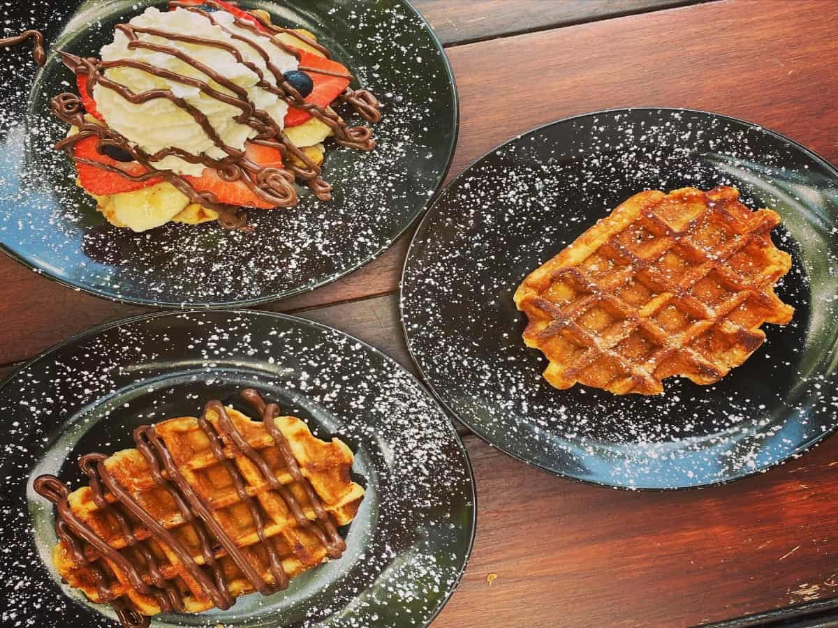 Three plates of waffles on a wooden table