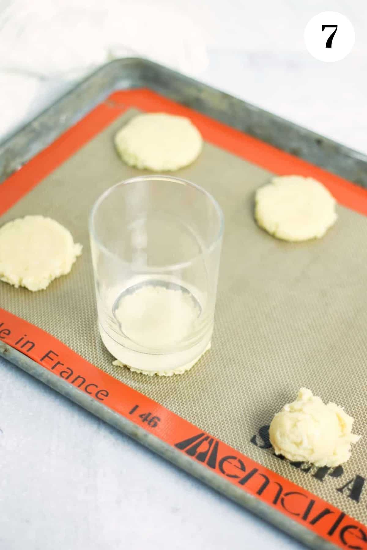 Using a glass to flatten the coconut lime cookies before baking.