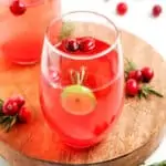 Two glasses of cranberry prosecco cocktail on a wooden board for Christmas.