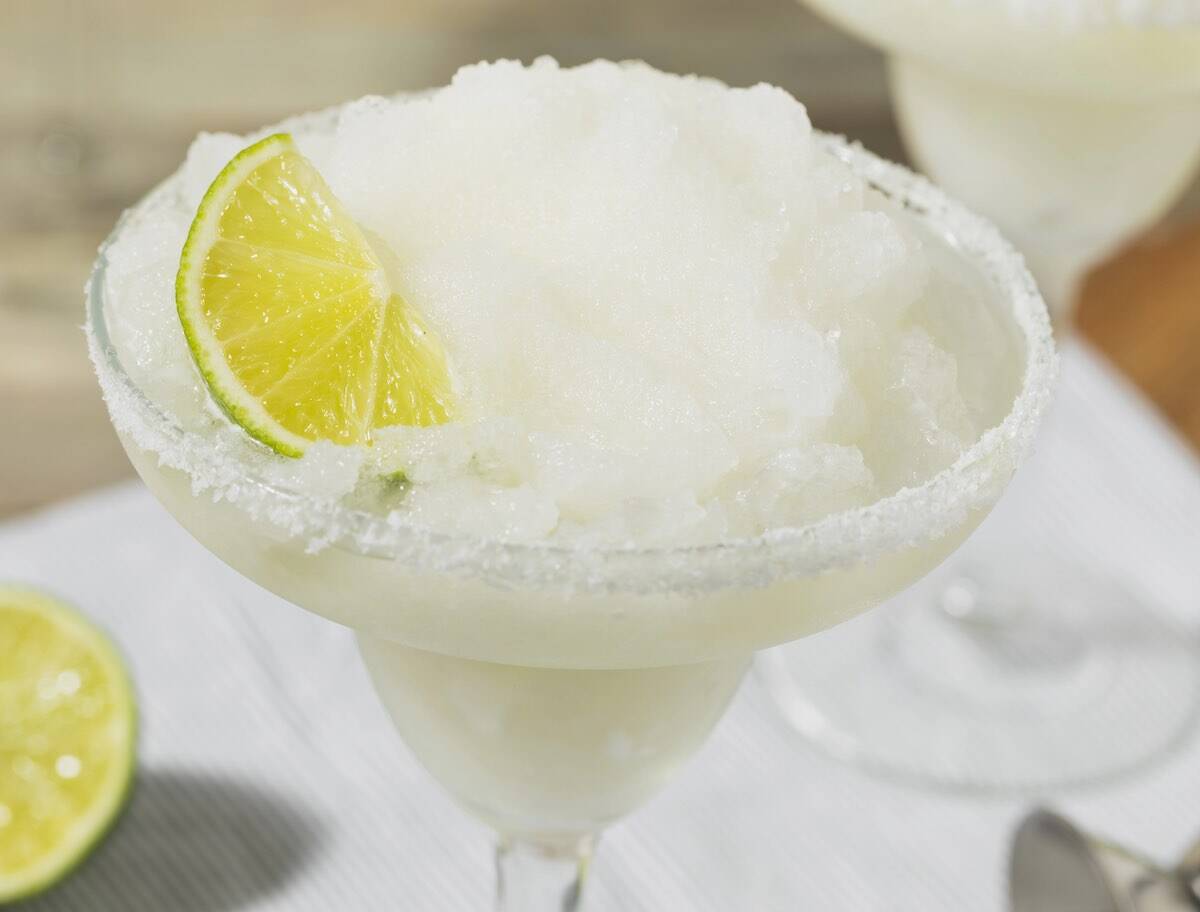 Frozen margarita in a glass on a white napkin outdoors.