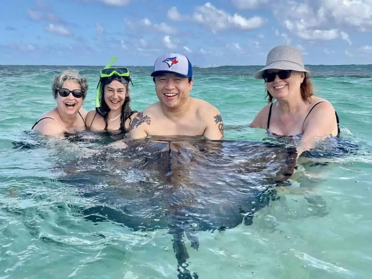 Four people with a wild stingray at Stingray City in Antigua.