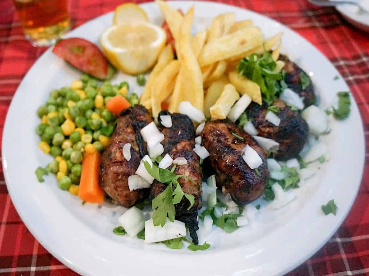 Sheftalies Cyprus sausage on a white plate with salad.