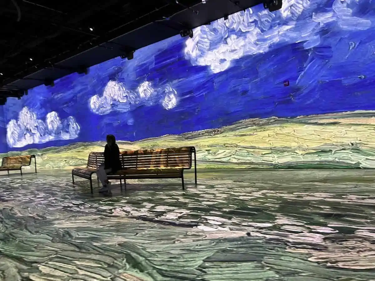 Person seated at Van Gogh Oasis Immersion exhibit in Montreal.