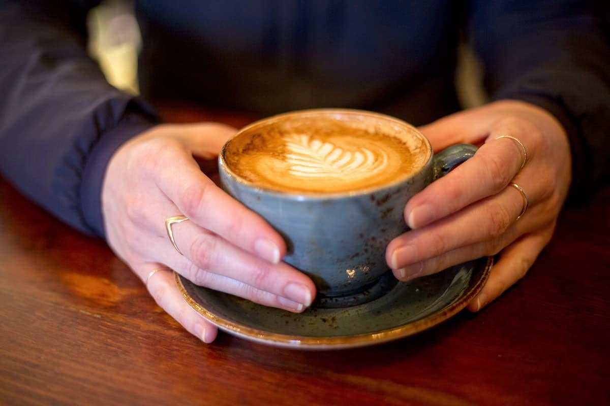 A person holding a cup of coffee at Forecast Coffee in Whistler, B.C. g