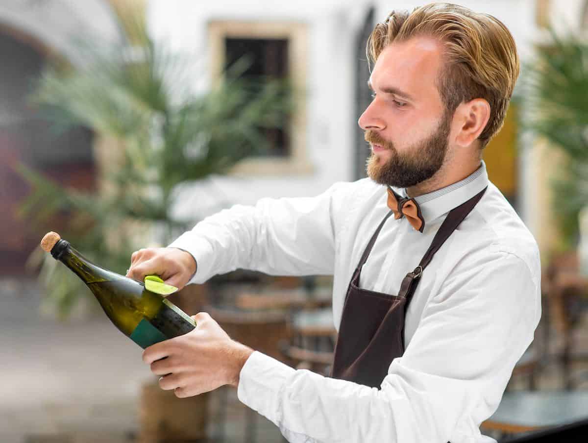 Bartender sabering a bottle of champagne.