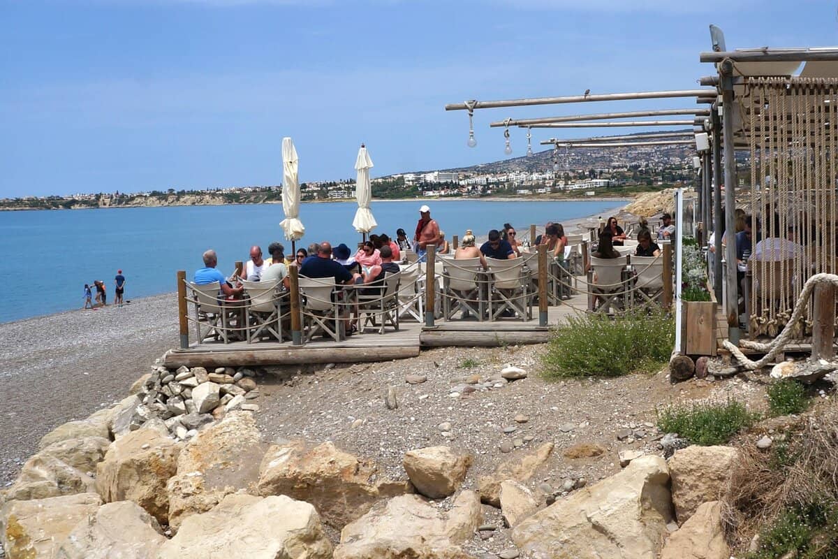 People seated at a beach bar at Potima Bay in Cyprus.