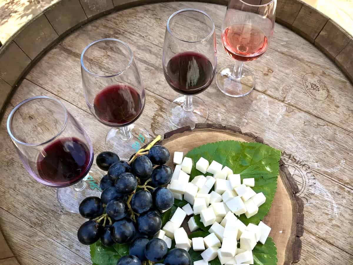 Four glasses of Turkish wines on a barrel with grapes and cheese. T