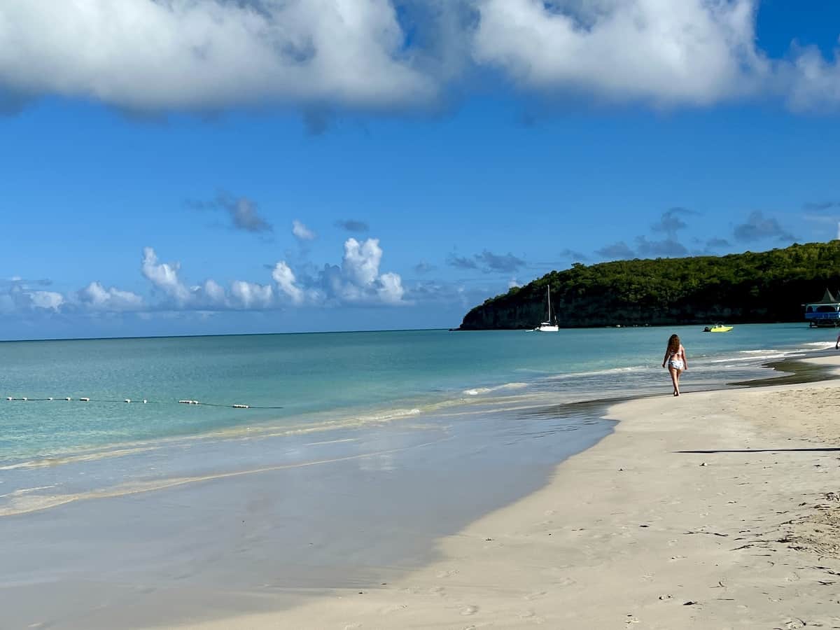 Woman in a bathing suit walking on Dickenson Bay Beach in Antigua.