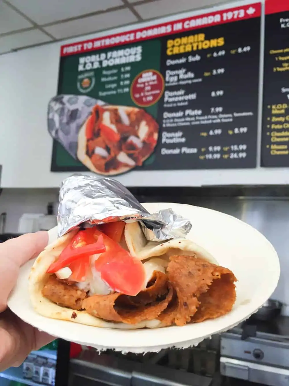 Donair on plate in front of menu.