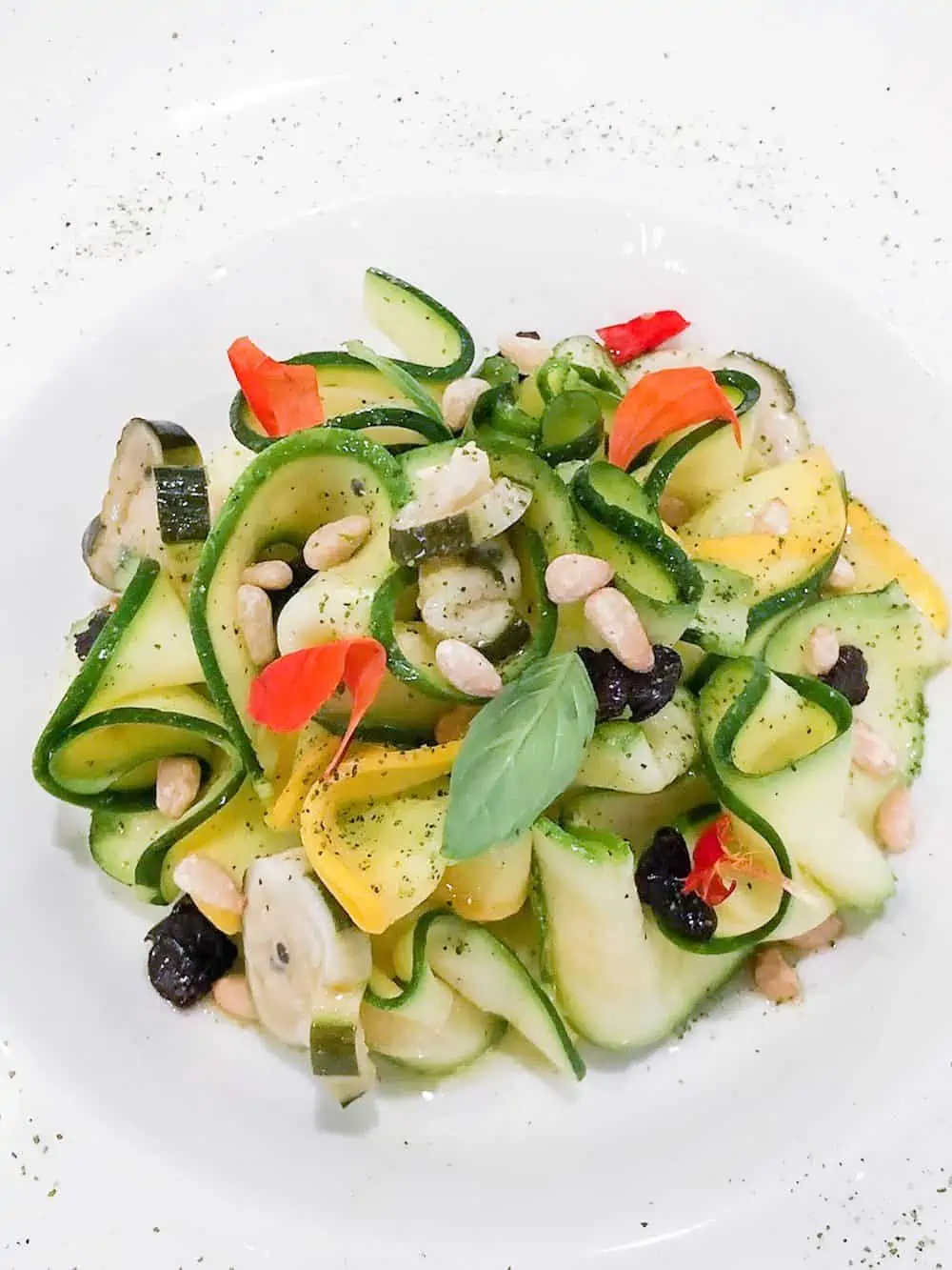 Shaved vegetables on white plate for an appetizer.