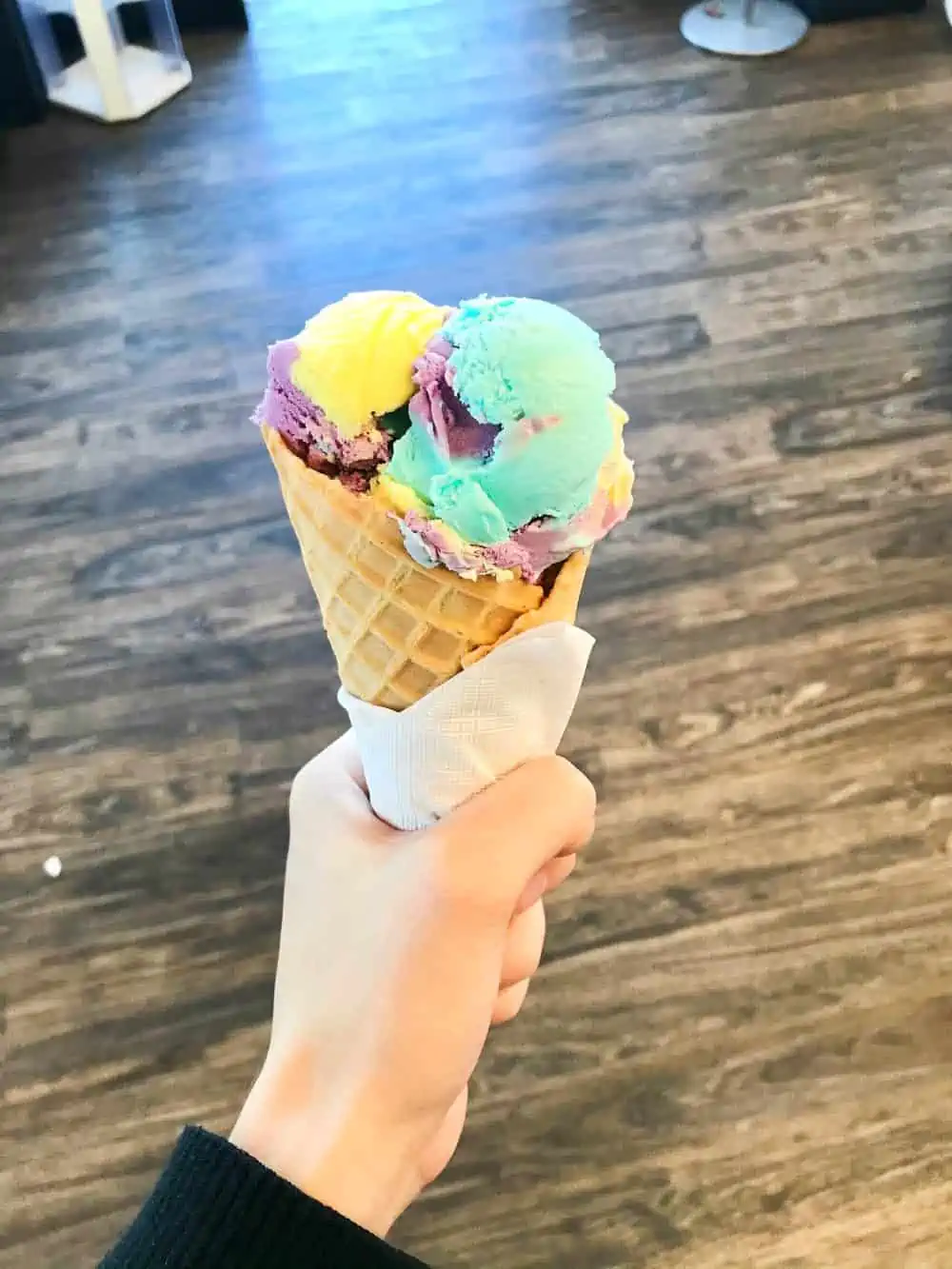 Moon Mist Ice Cream in waffle cone in hand.