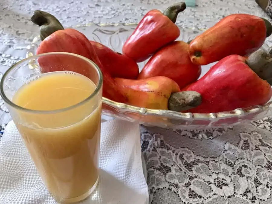 A glass of mariñon juice with a bowl of marinon fruit.