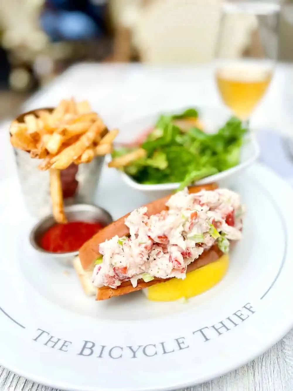 Lobster Roll on white plate with fries and salad in Halifax.