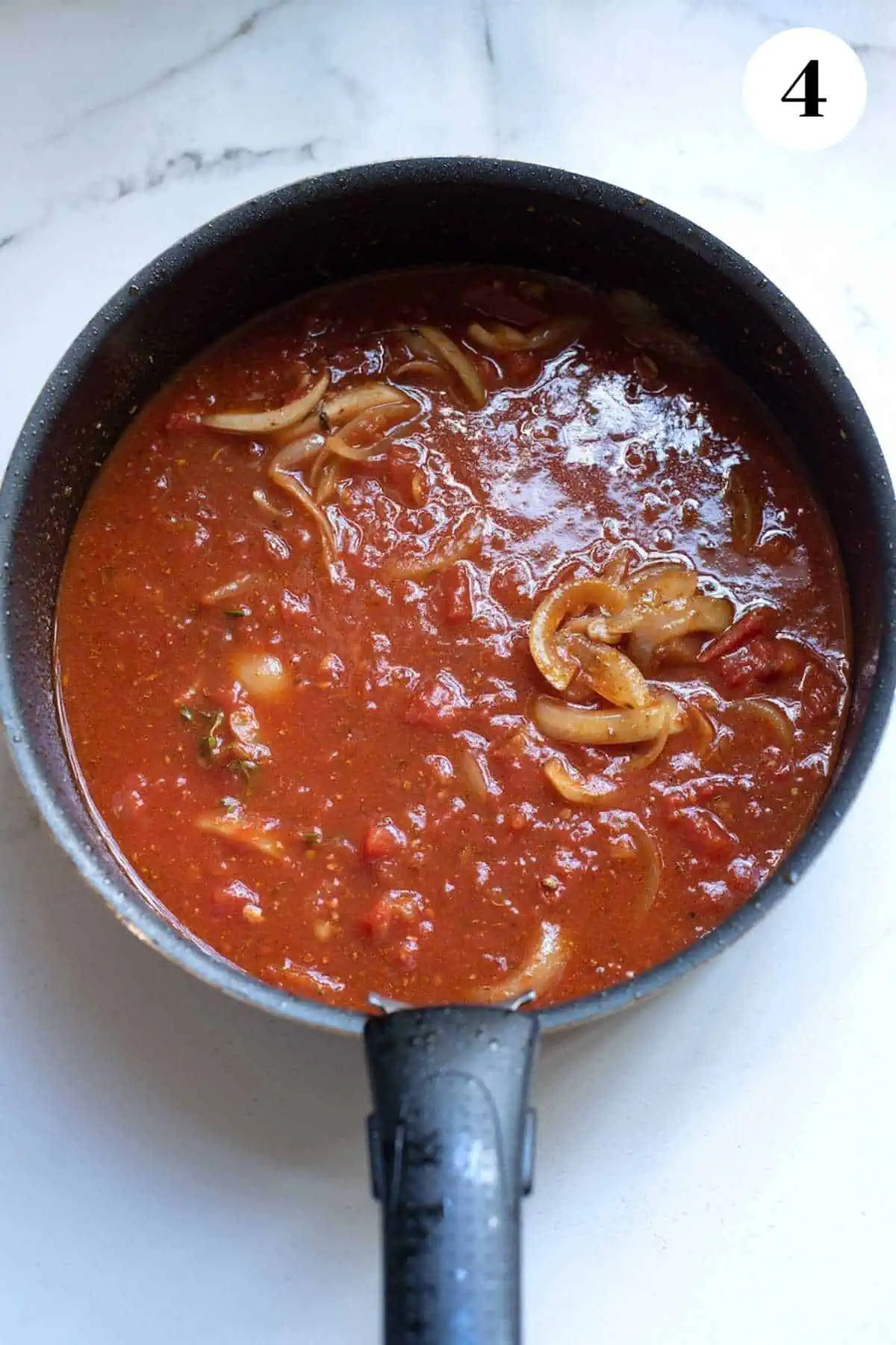 Tomato sauce simmering in a cast iron pan.