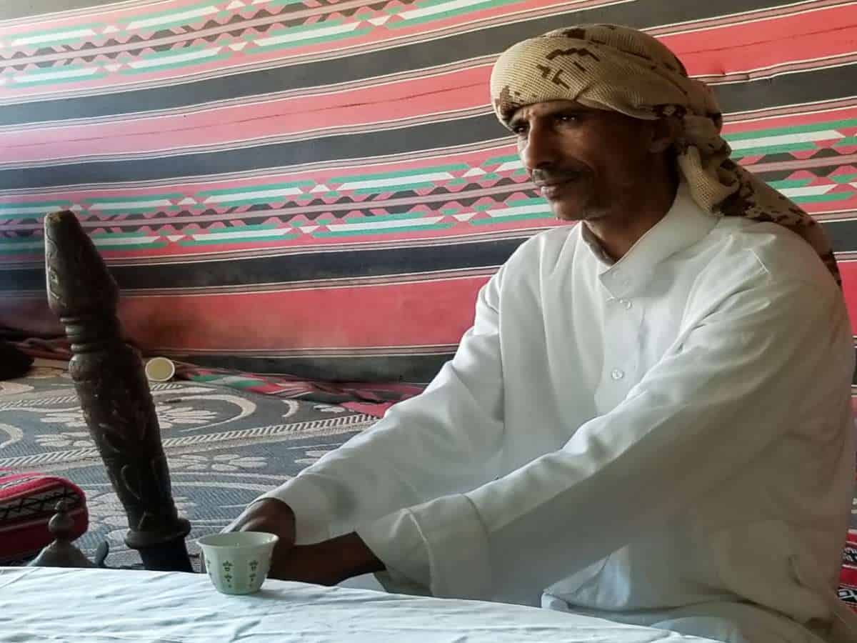 Bedouin man enjoying coffee at table.