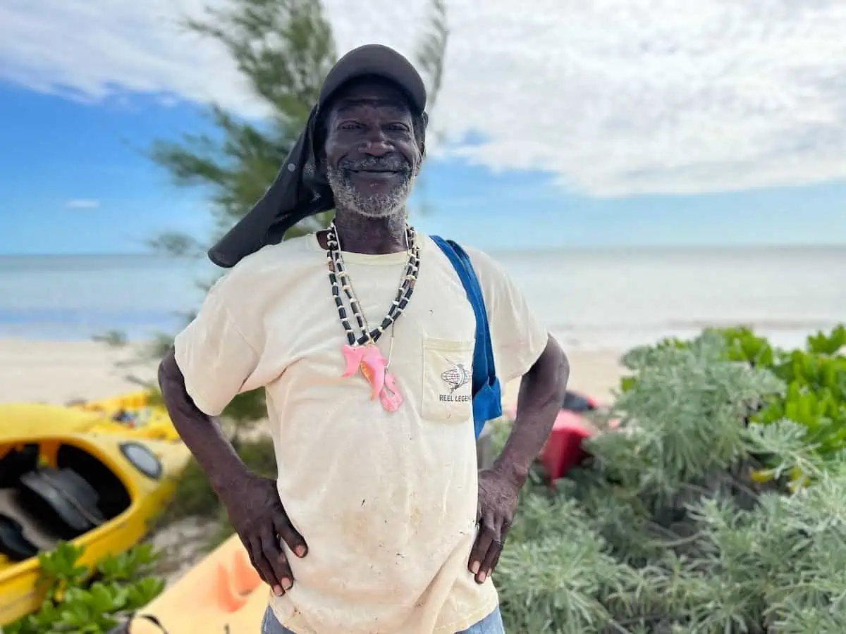 Craftsman in front of kayak and beach.