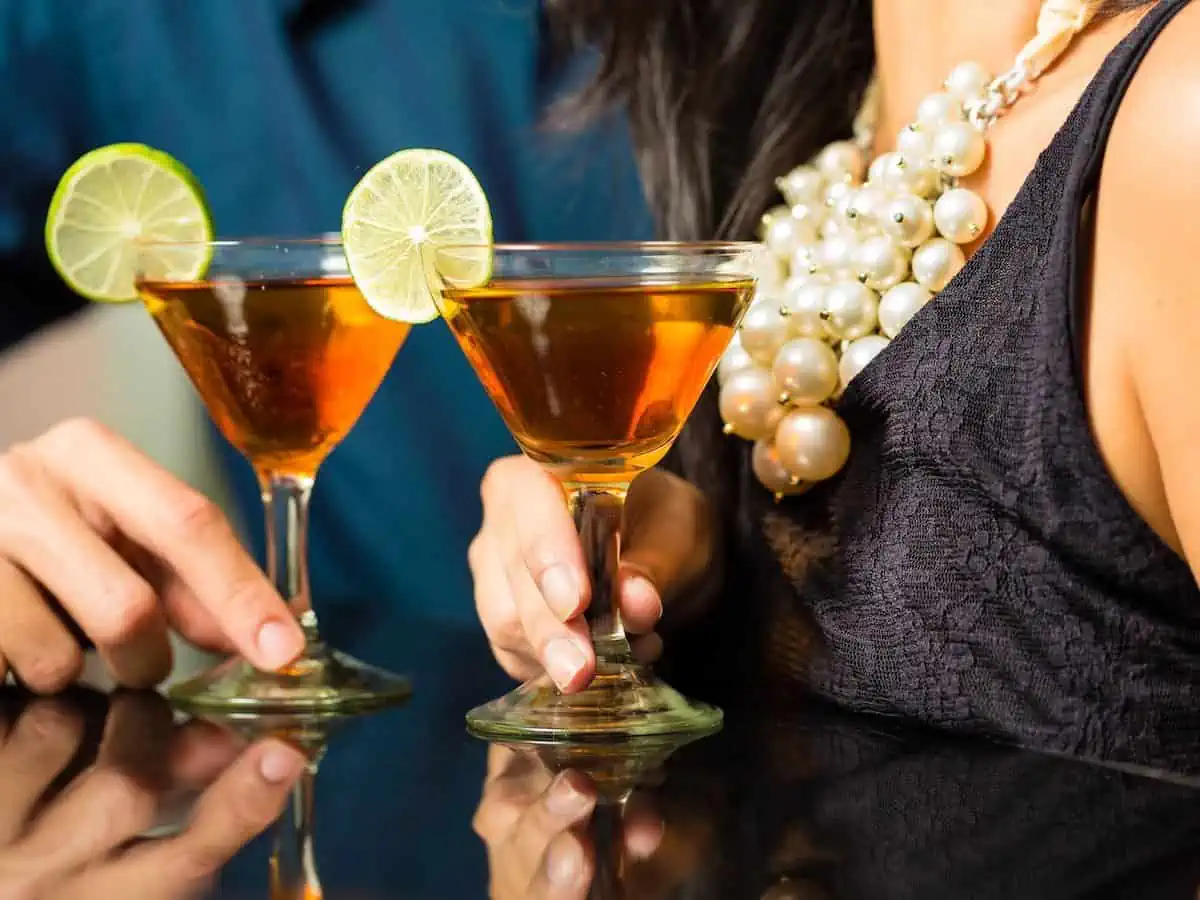 A couple holding cocktails on a romantic evening.  