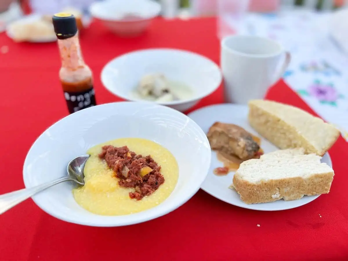 Corned beef and grits in white bowl on red table cloth. 