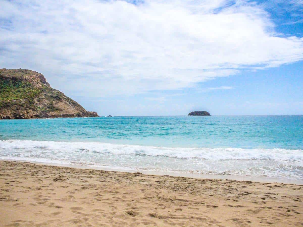 Ocean view with sand and mountains.