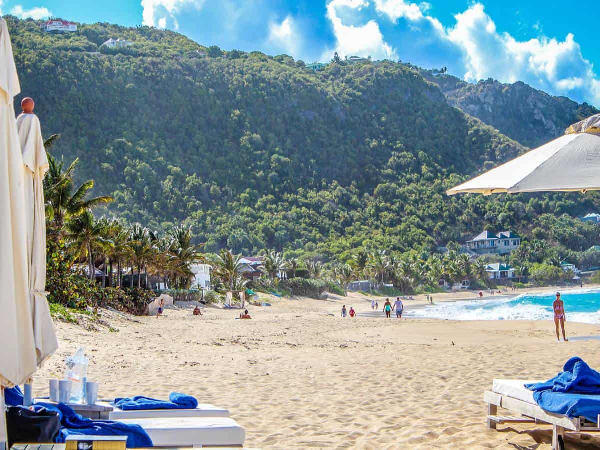 Sandy beach in St. Barts with people walking.