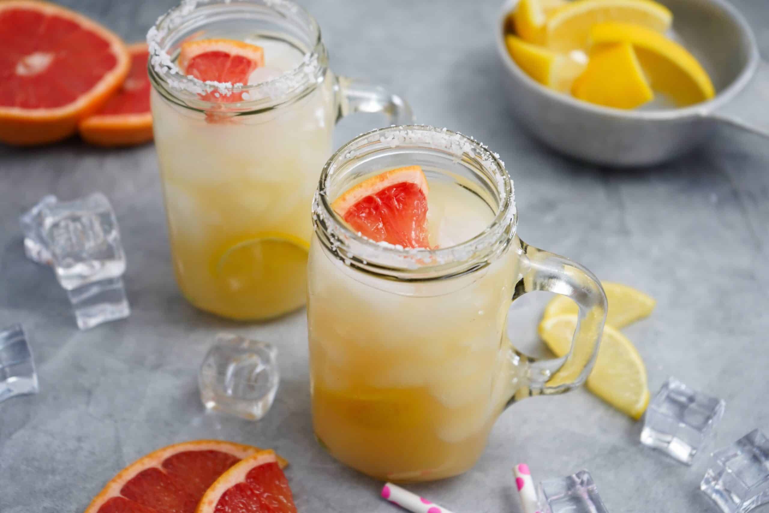 Two mason jar glasses with a mescal cocktail garnished with grapefruit. 