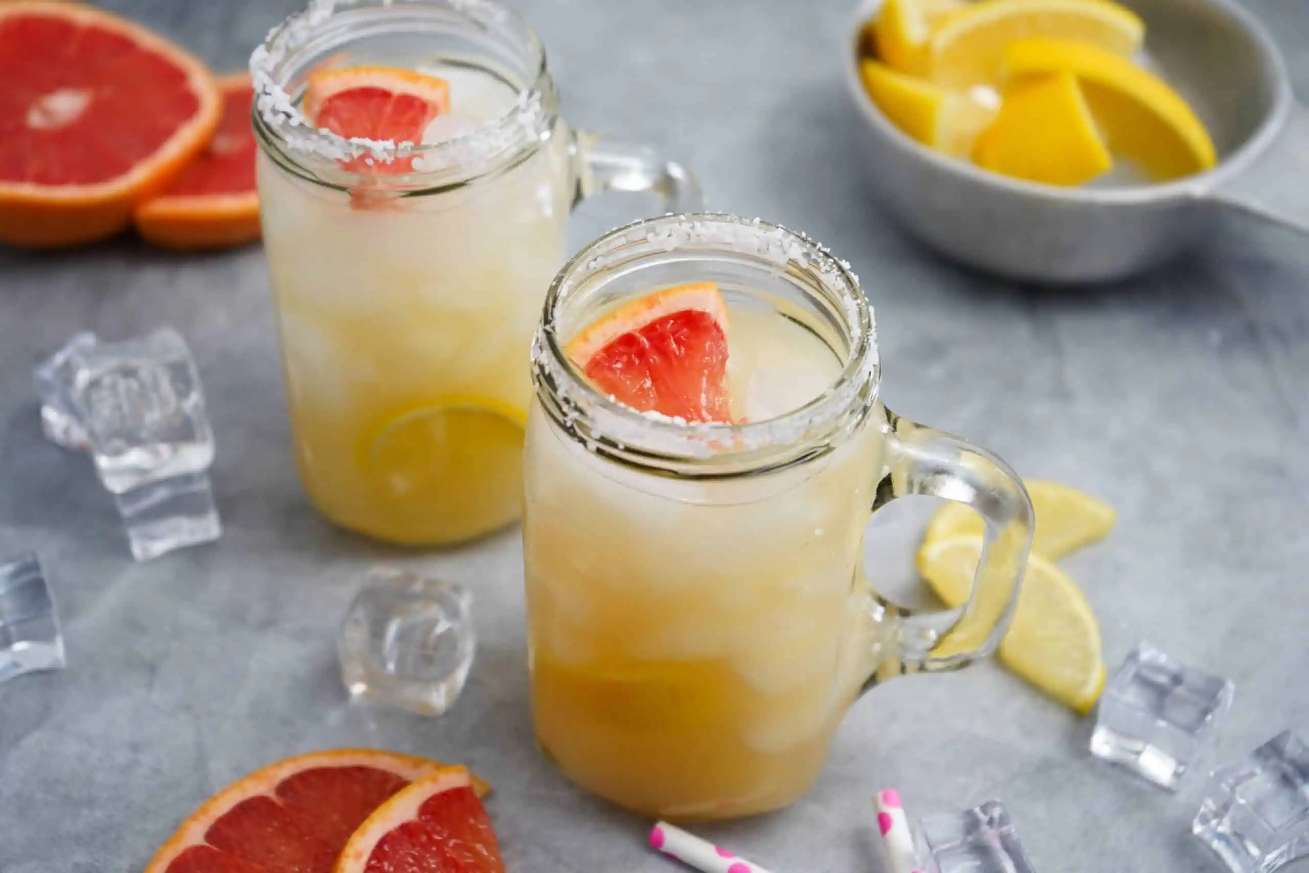 Two mason jar glasses with a mescal cocktail garnished with grapefruit. 