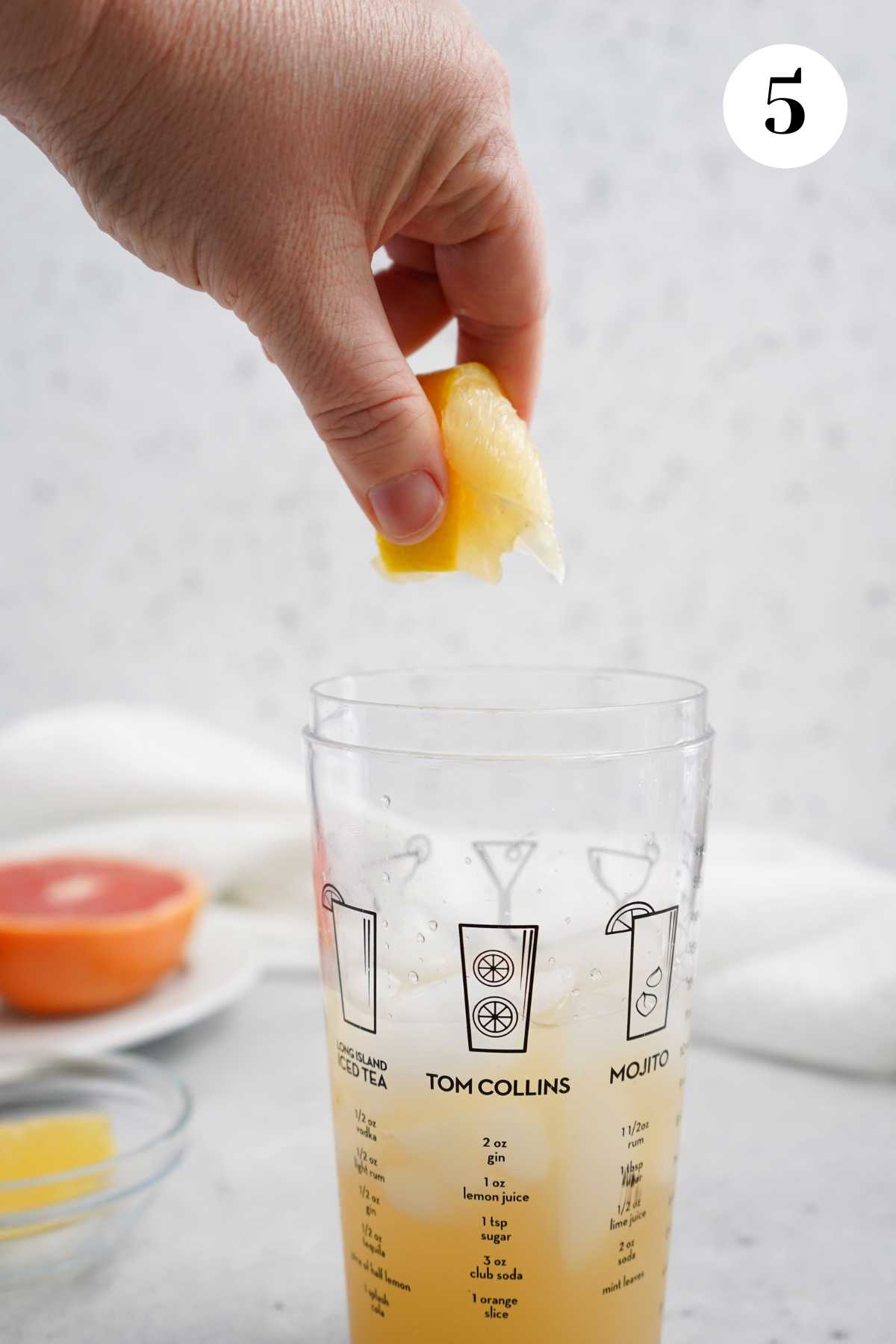 Squeezing the fresh lemon into the shaker glass.