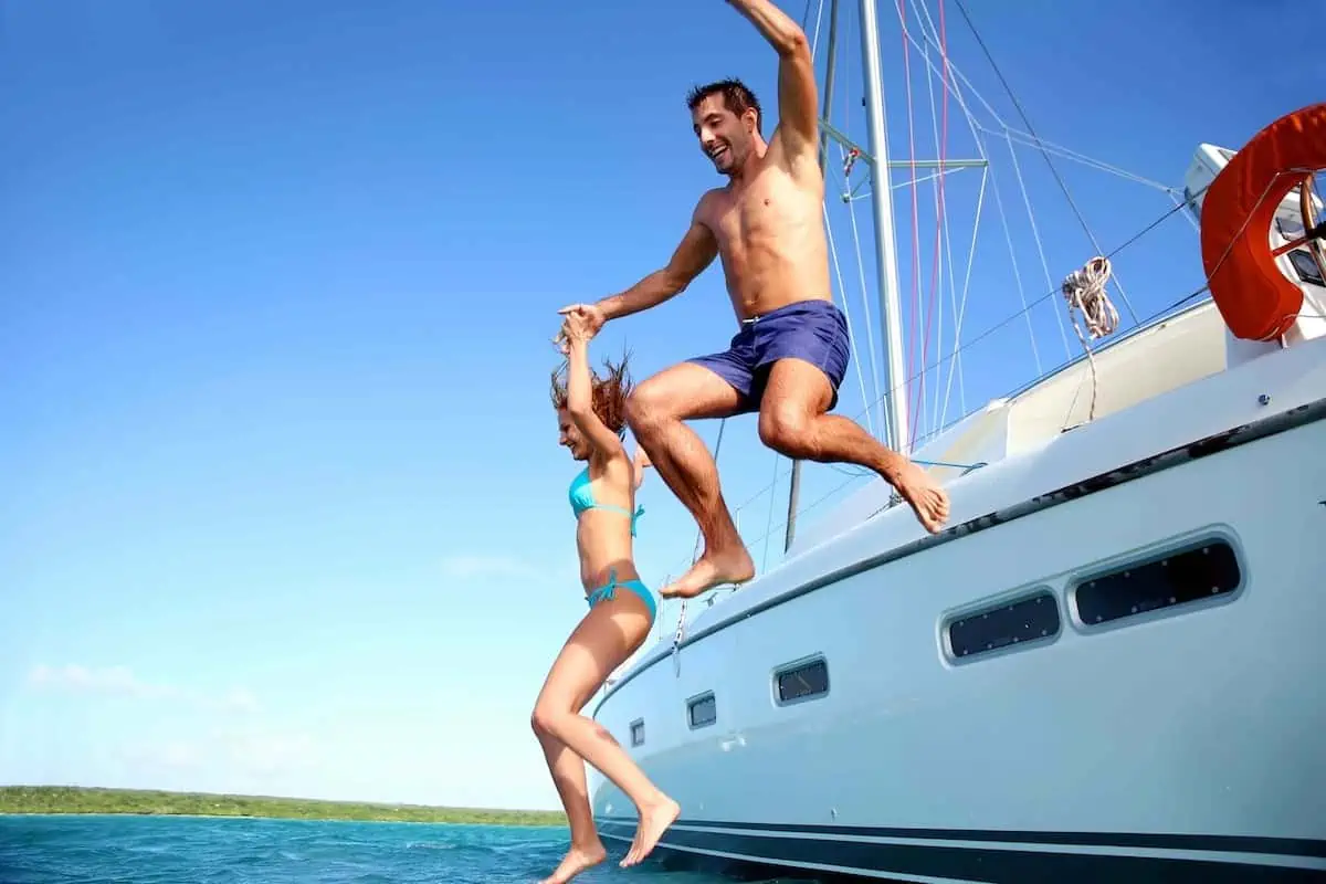 Couple jumping off a boat into the water.  