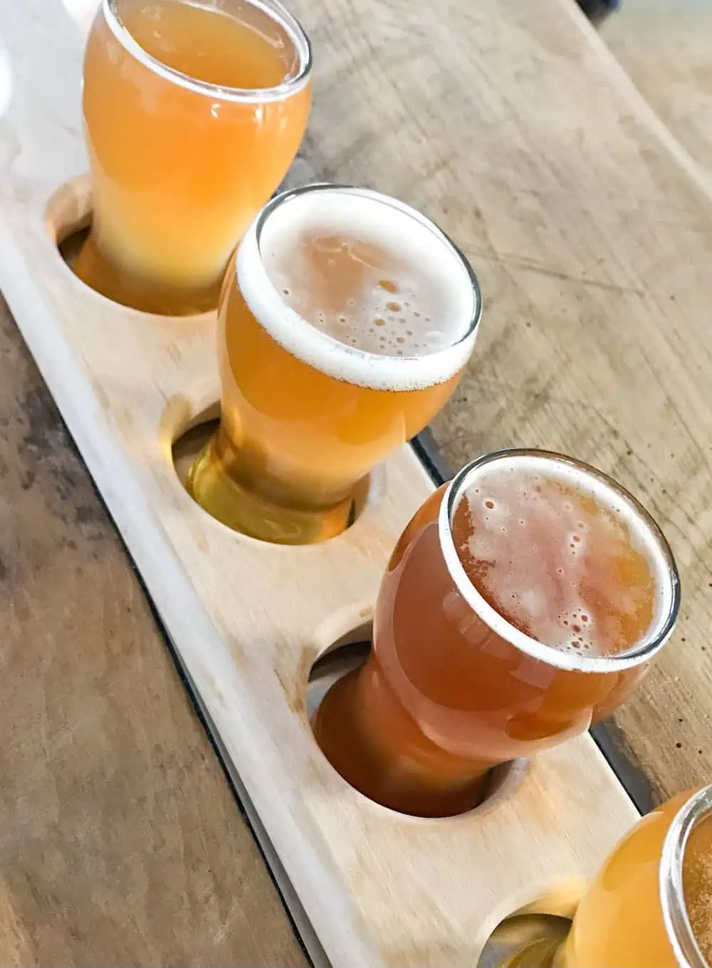 A flight of craft beer on a wooden tray. 