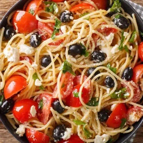 Greek pasta salad in a black bowl.