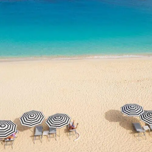 Overhead view of a beach in Anguilla with umbrellas on the sand.