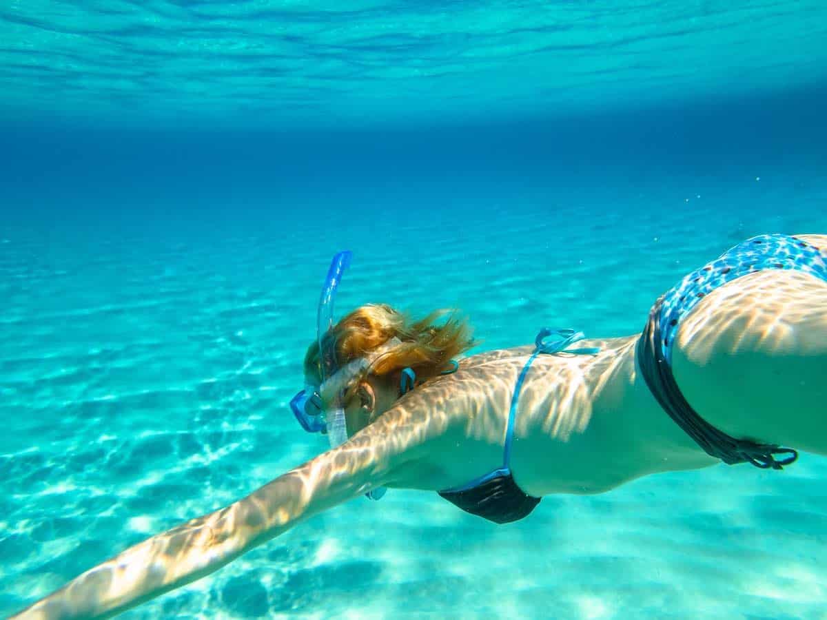 Young woman snorkeling in clear blue water. 
