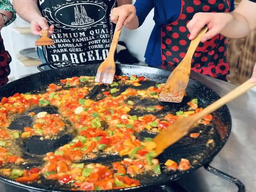 Cooking paella with wooden spoons at a Cookly Barcelona Cooking Class.